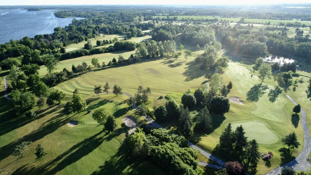 An aerial view of a golf course surrounded by trees and a lake.