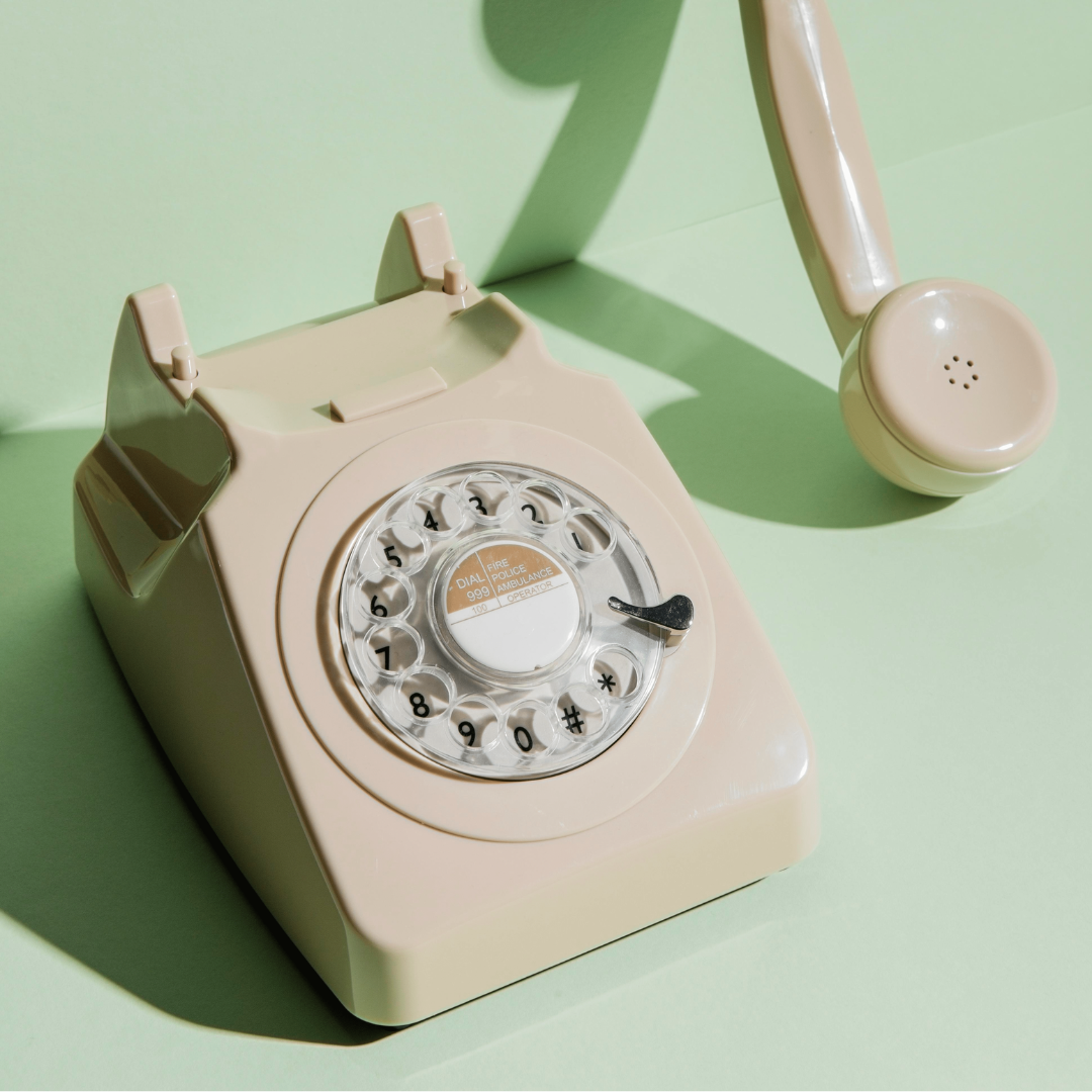 A white rotary phone on a green backdrop