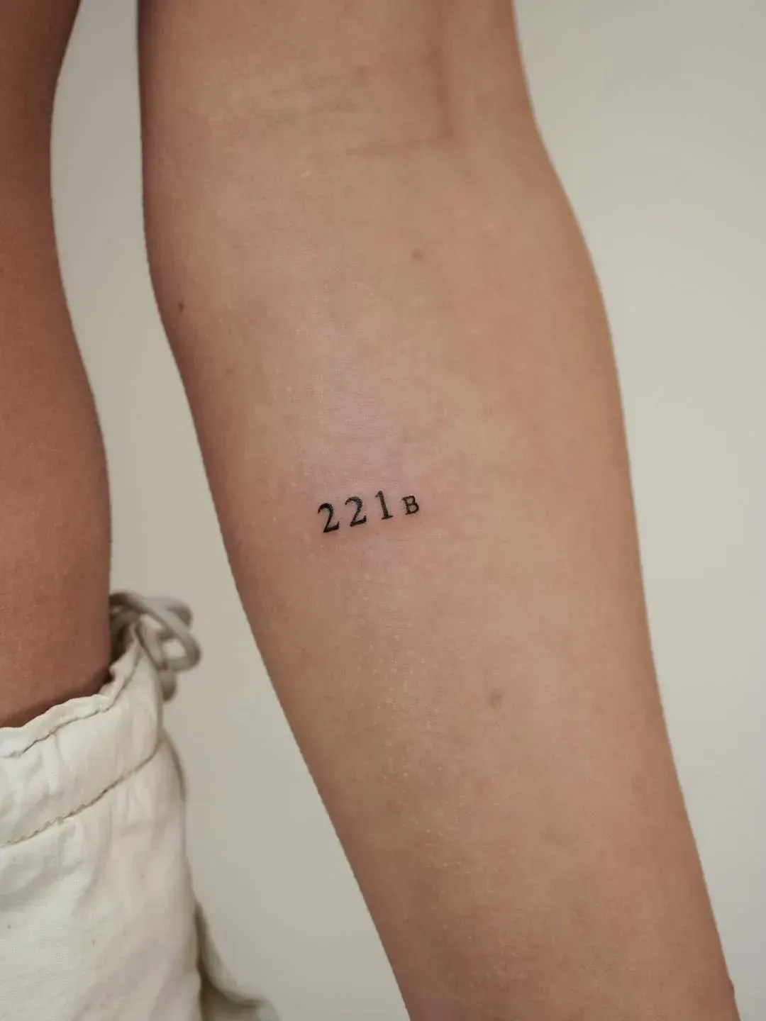 A small, simple black ink tattoo on a person's forearm that reads 