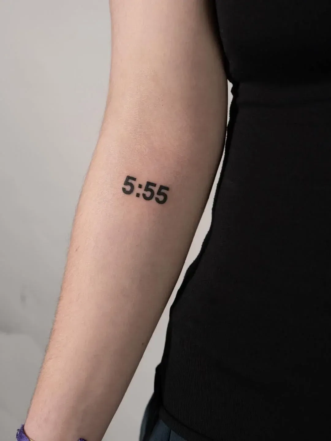 A small, black, sans-serif tattoo of the numbers 