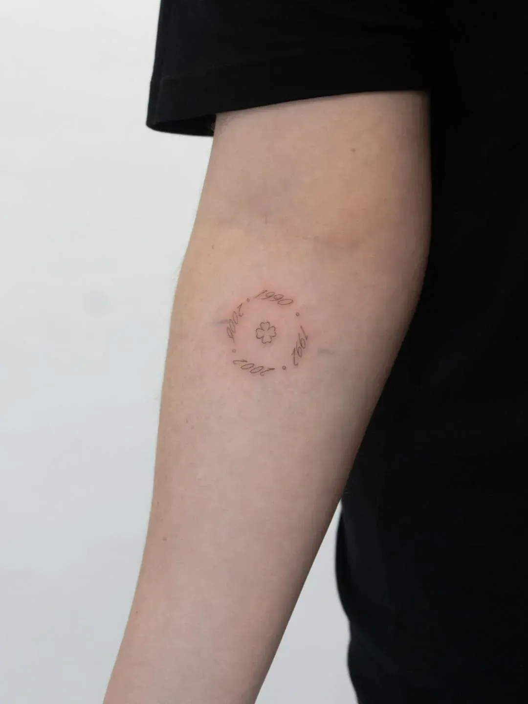 A small, delicate tattoo of a circular, floral-inspired geometric design on a person's inner forearm.