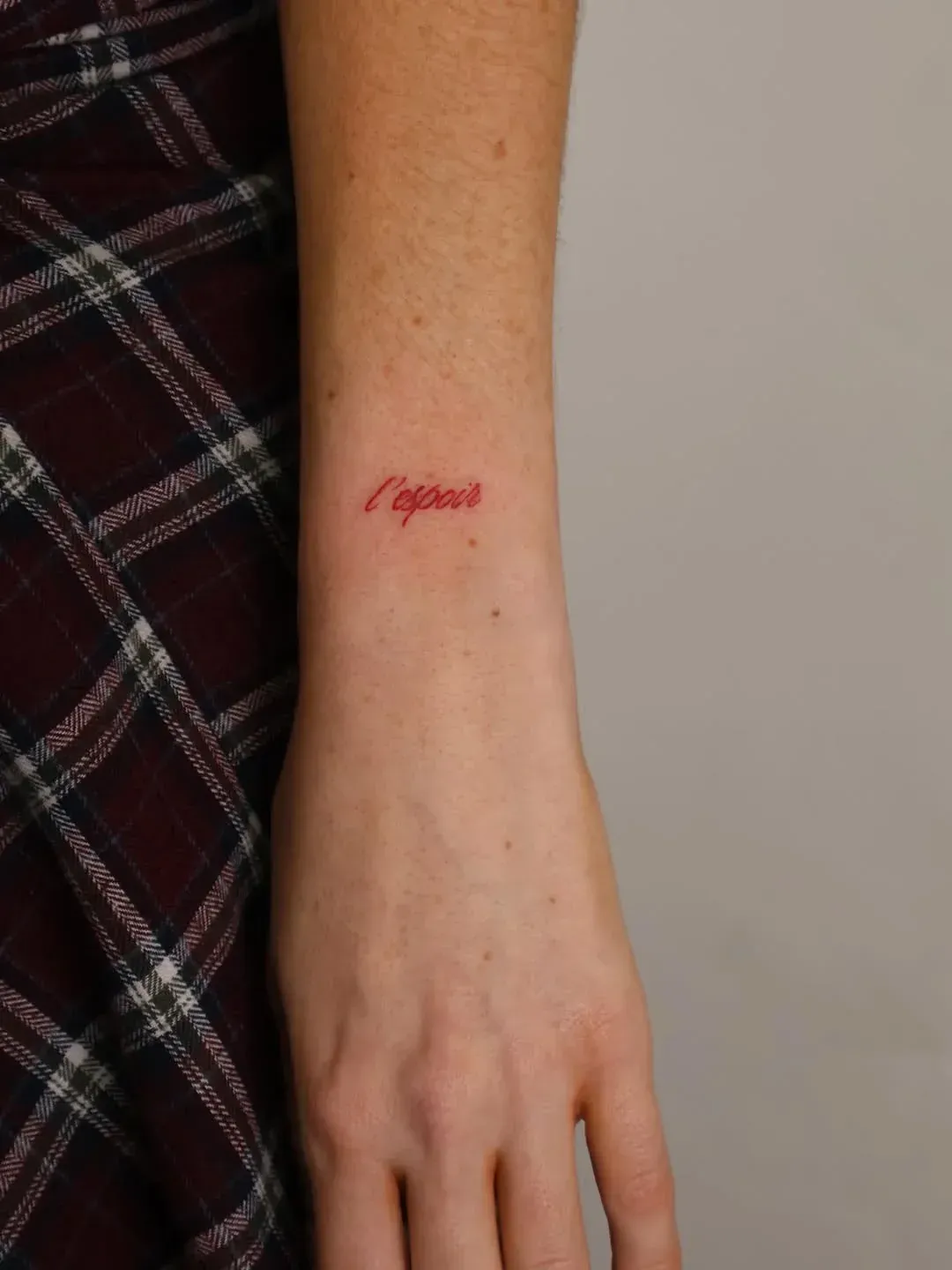 A small, red, cursive tattoo that reads 