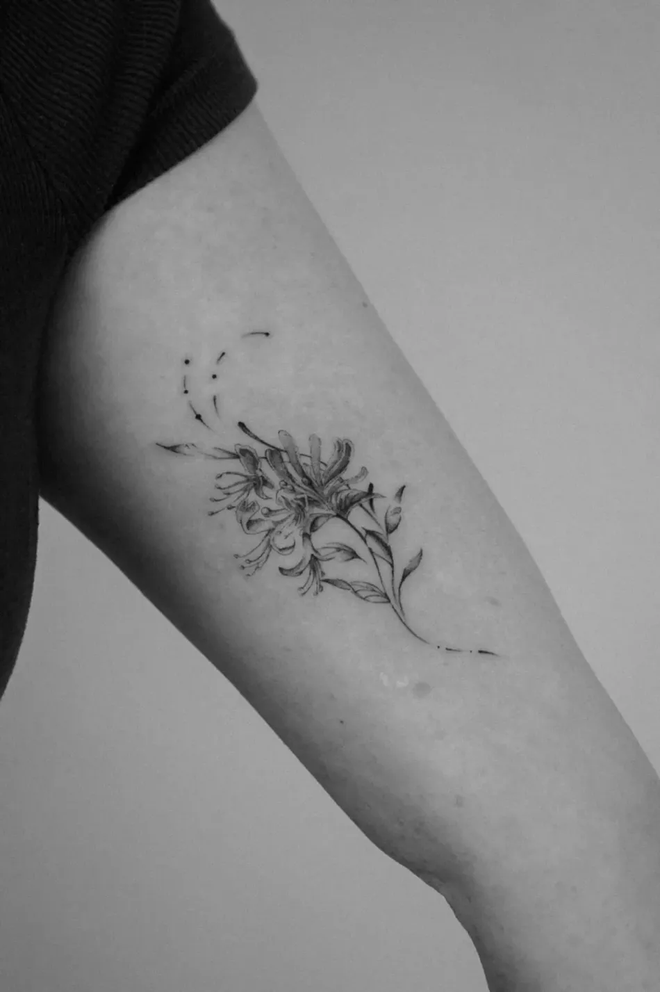 A delicate, fine-line tattoo of trailing ivy vines and small leaves winding along the side of a person's torso.