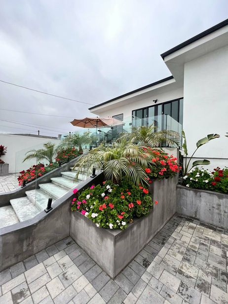 Exterior view of a modern house with a staircase lined with flower boxes and a cloudy sky.