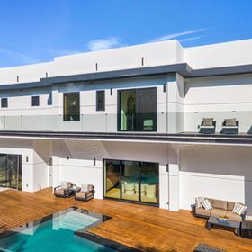 Modern white house with a pool and wooden deck.