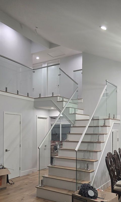 Staircase with glass railing, white walls, and wood steps in a modern interior.