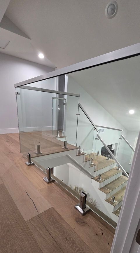 Glass staircase with metal supports and wooden flooring.