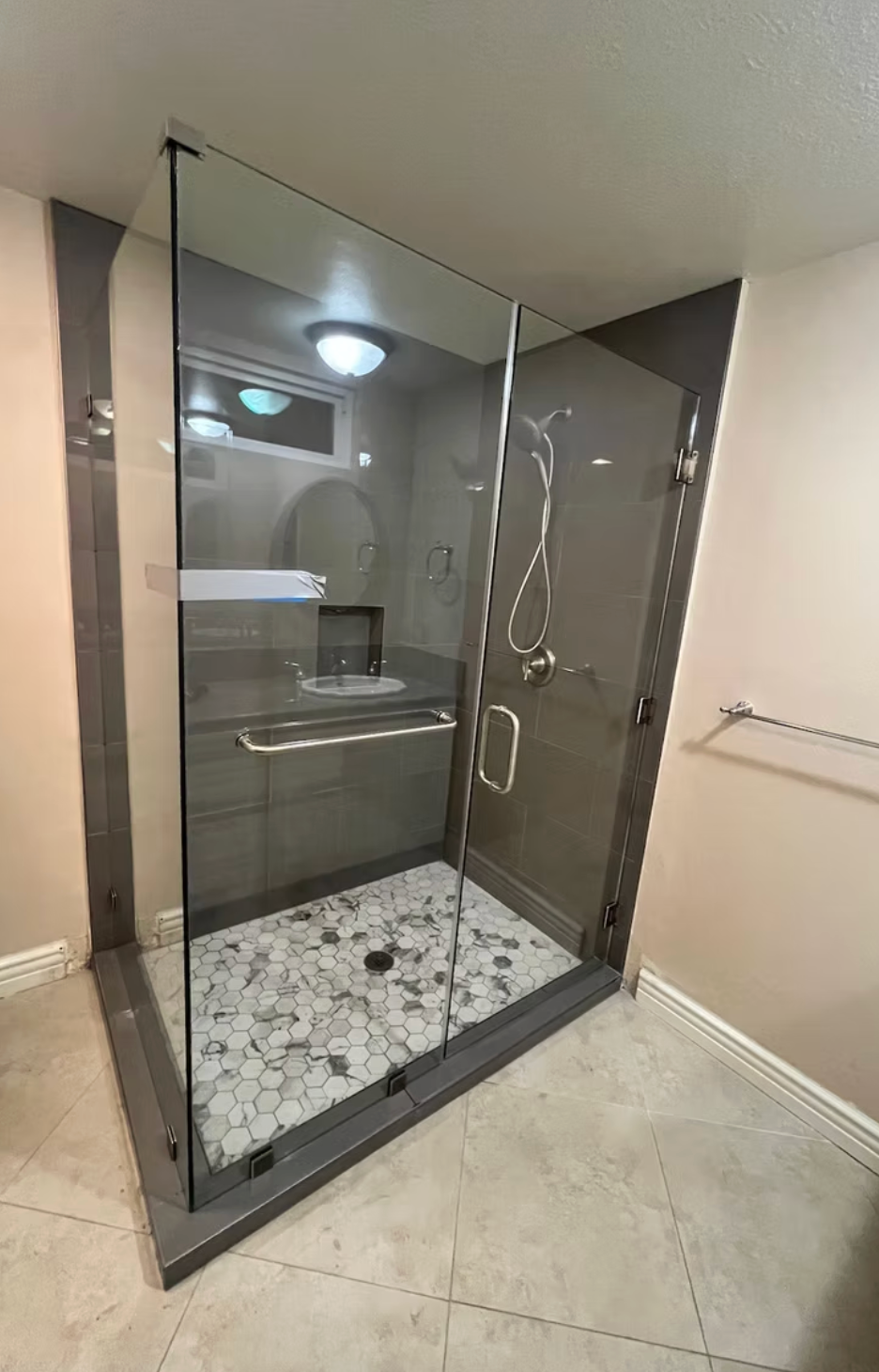 Modern bathroom with marble walls and flooring, glass shower, toilet, and sink.