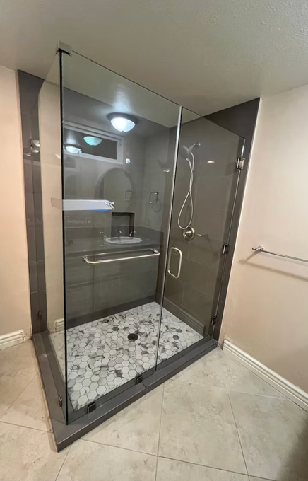 Modern bathroom with marble walls and flooring, glass shower, toilet, and sink.