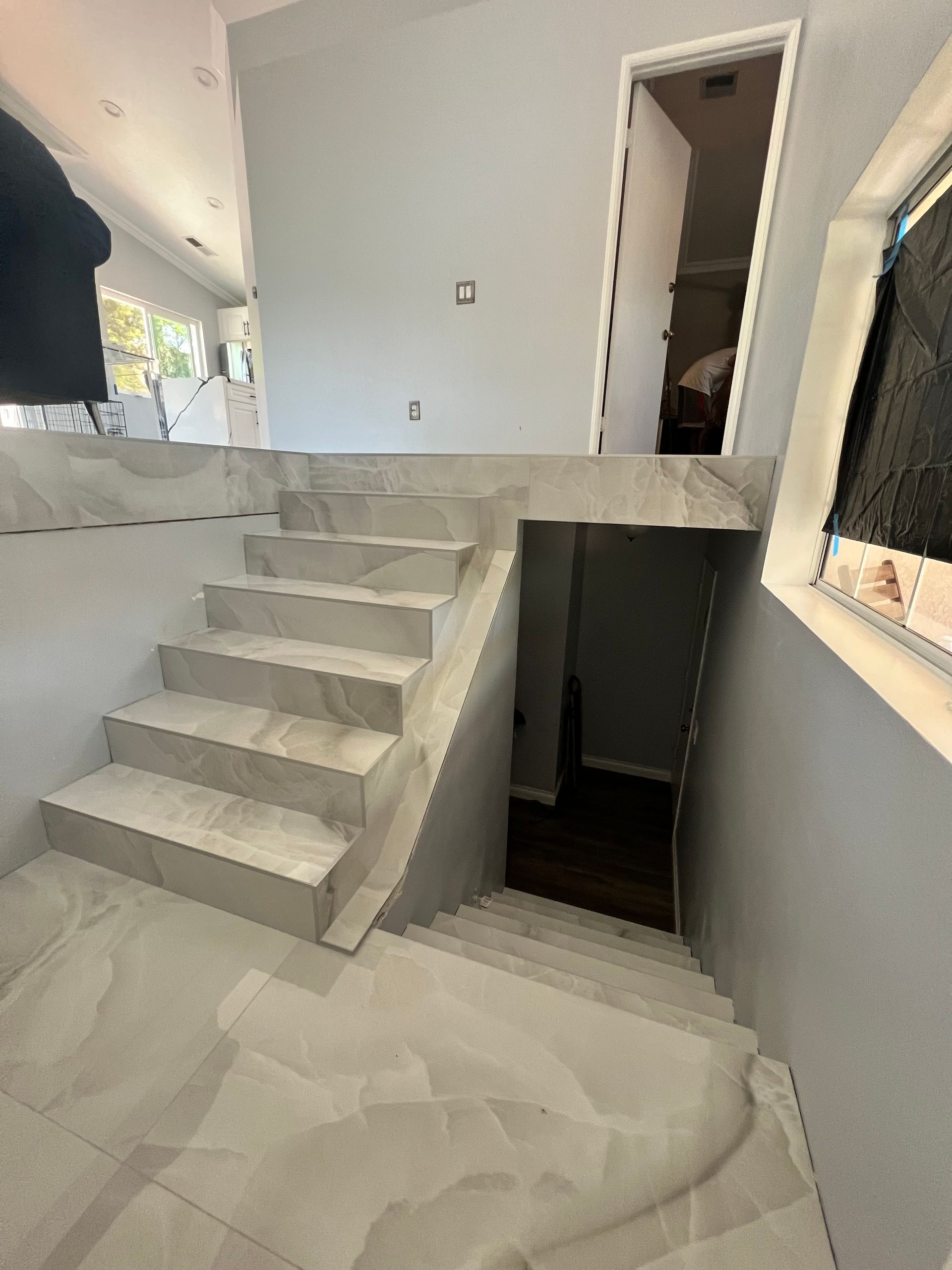 Staircase with light-colored tile leading down from an elevated landing. A doorway is at the top.