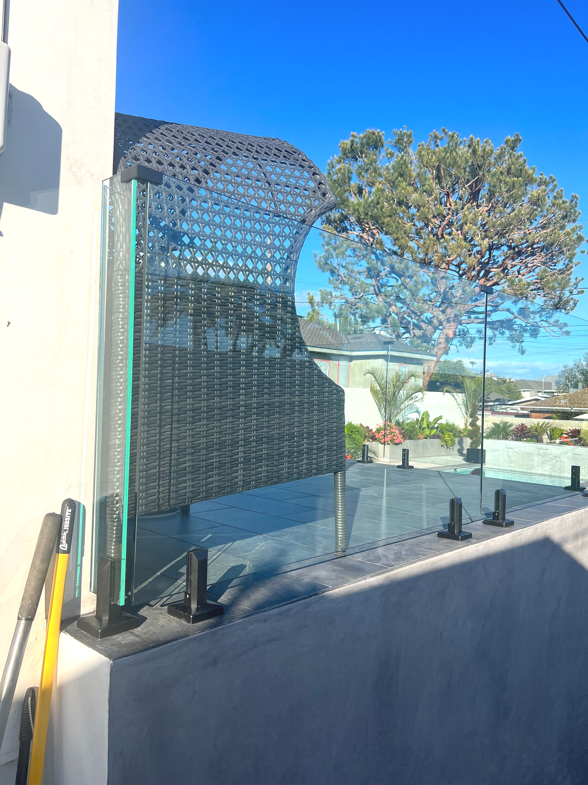 Glass balcony railing with a decorative privacy screen, sunny outdoors.