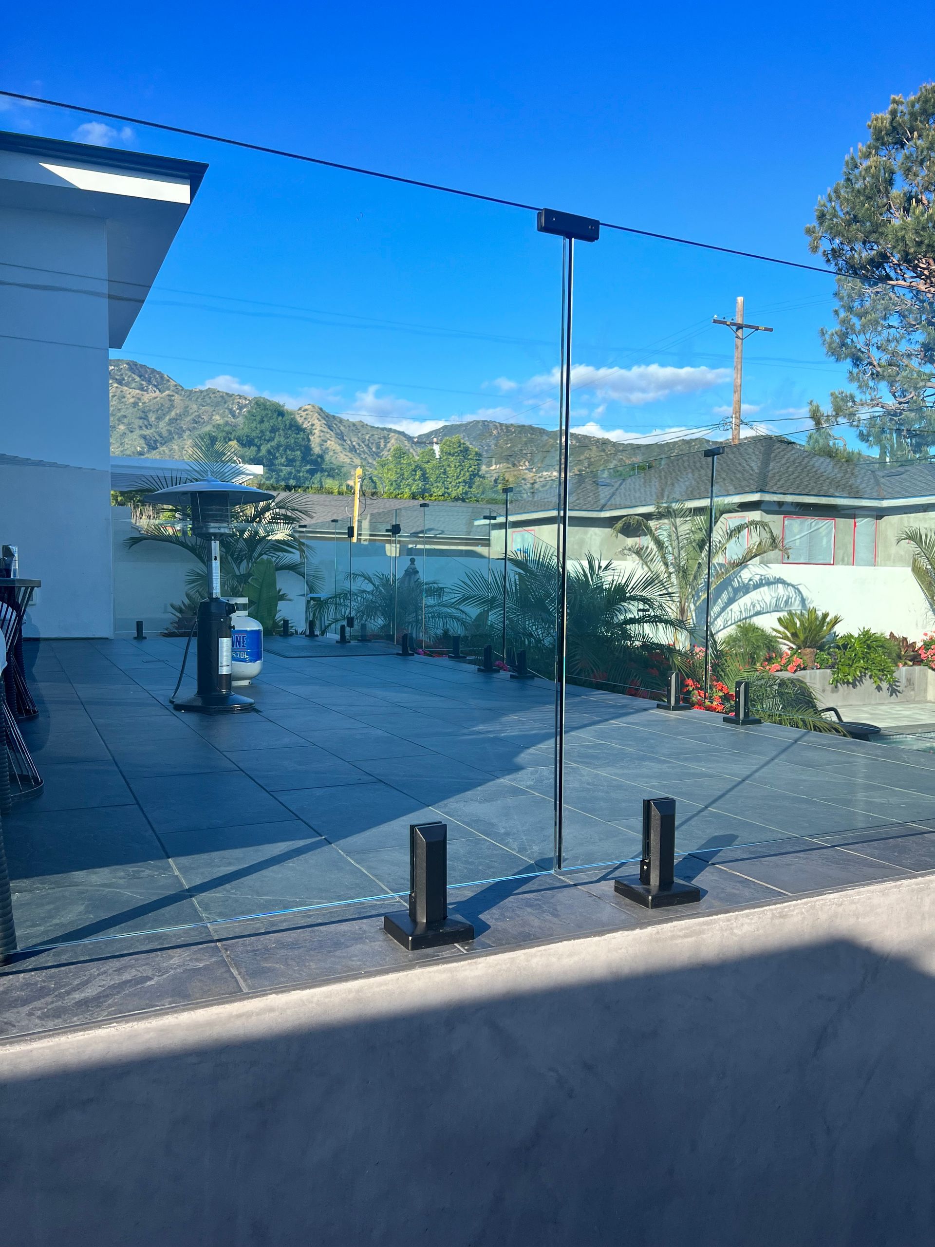 Glass fence on a patio, mountains and blue sky in the background.