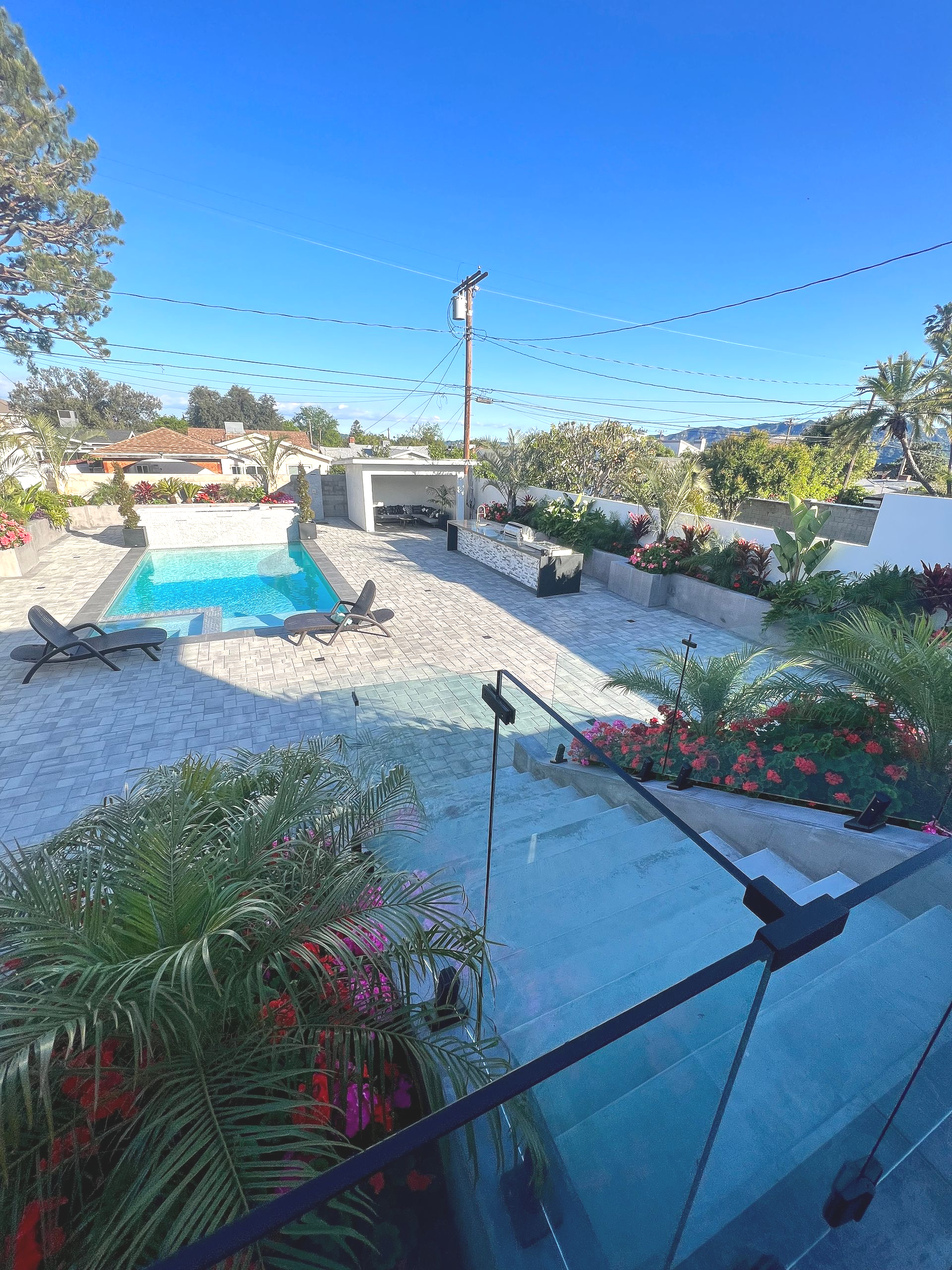 Outdoor patio with a pool, seating, and a clear blue sky.