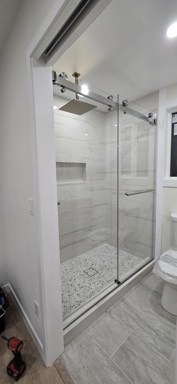 Modern bathroom with marble walls and flooring, glass shower, toilet, and sink.