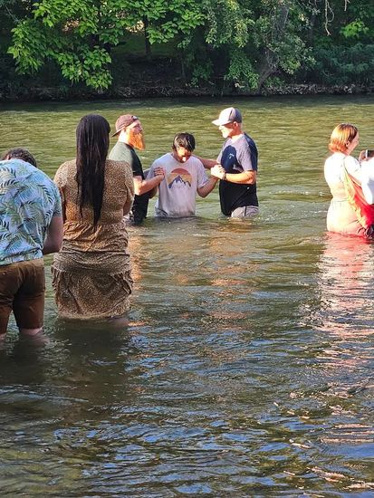 A group of people are standing in a body of water.
