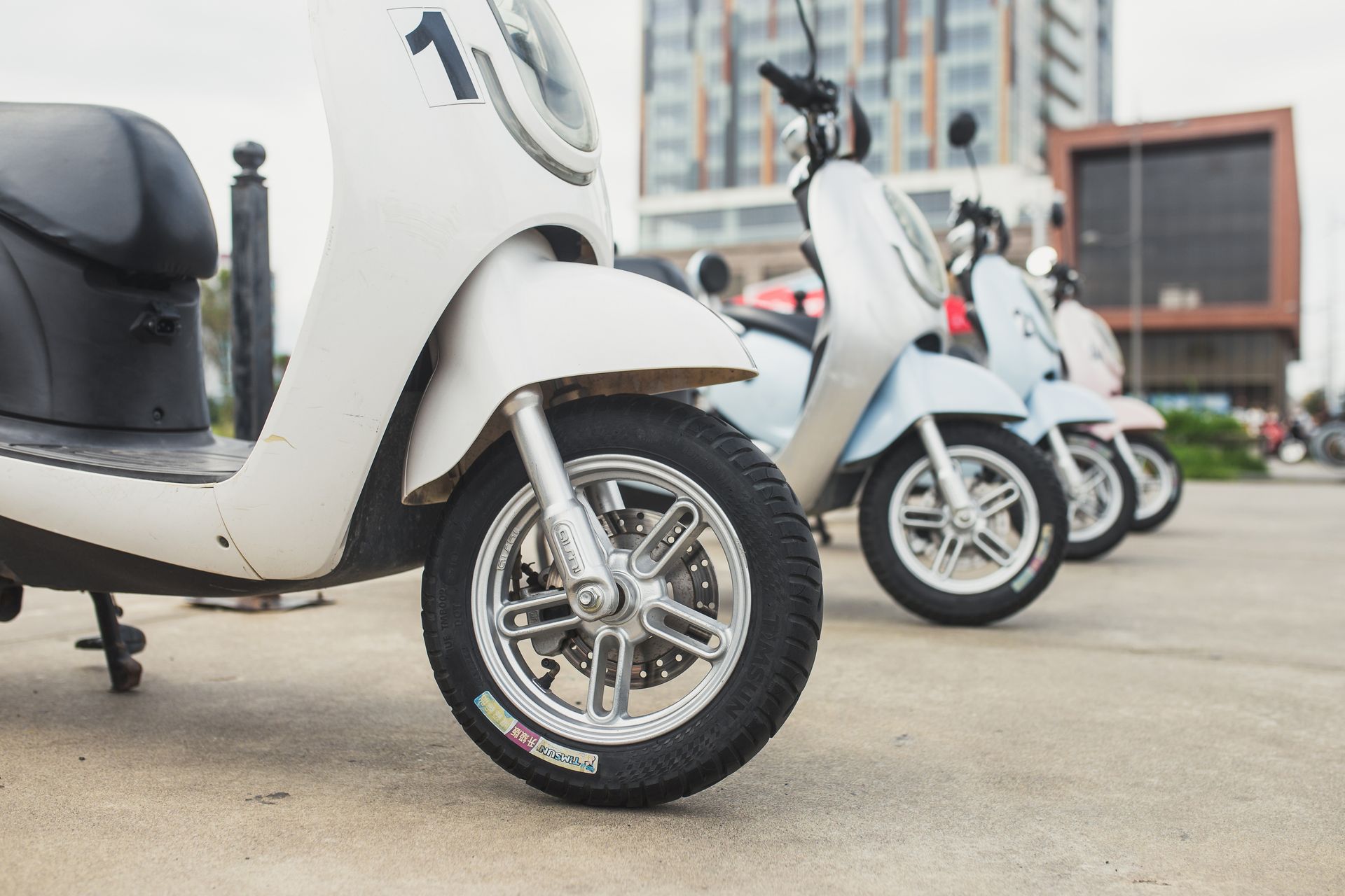 Une rangée de scooters est garée sur un parking.