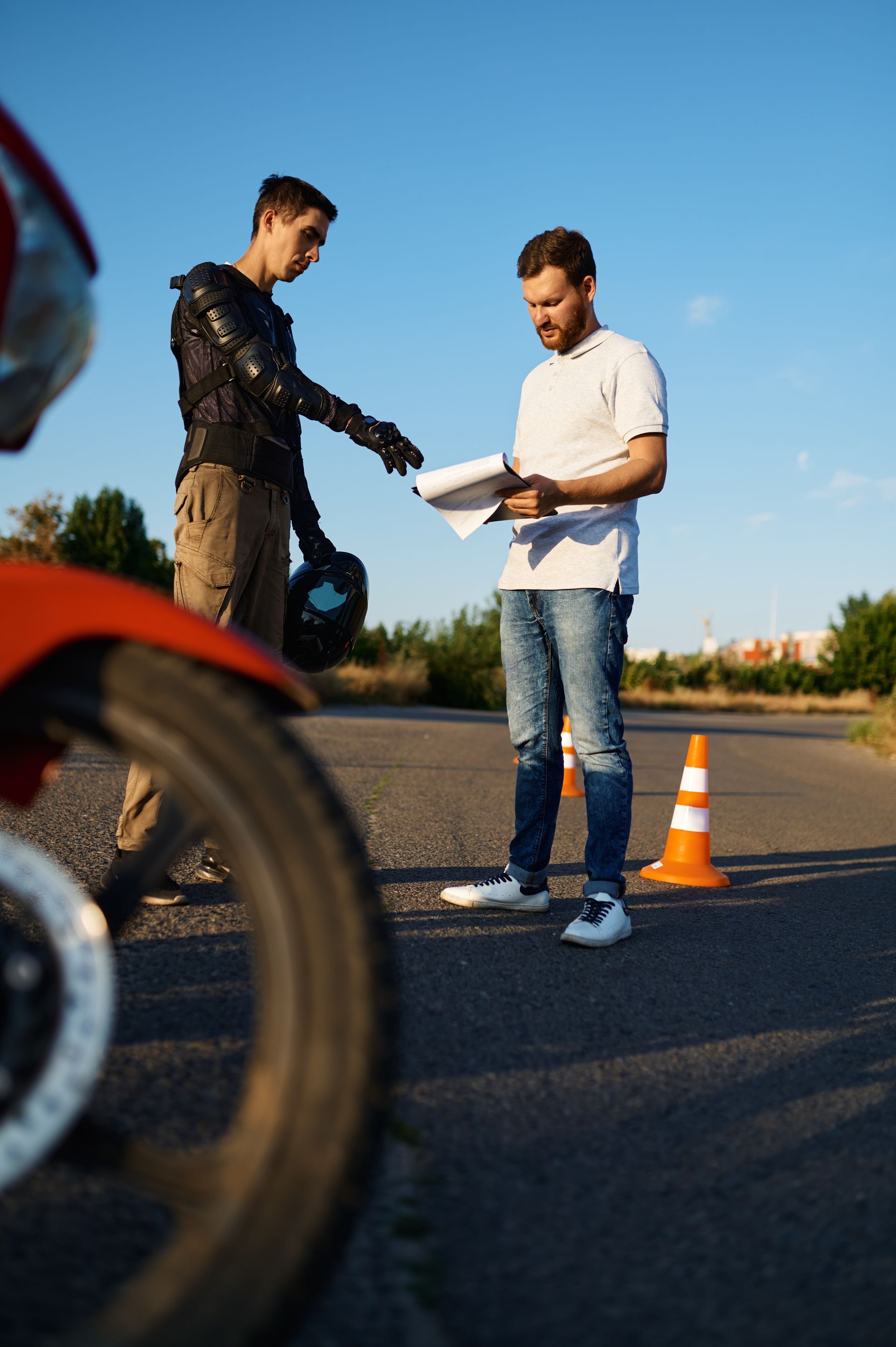 Deux hommes se tiennent à côté d'une moto sur le bord de la route.
