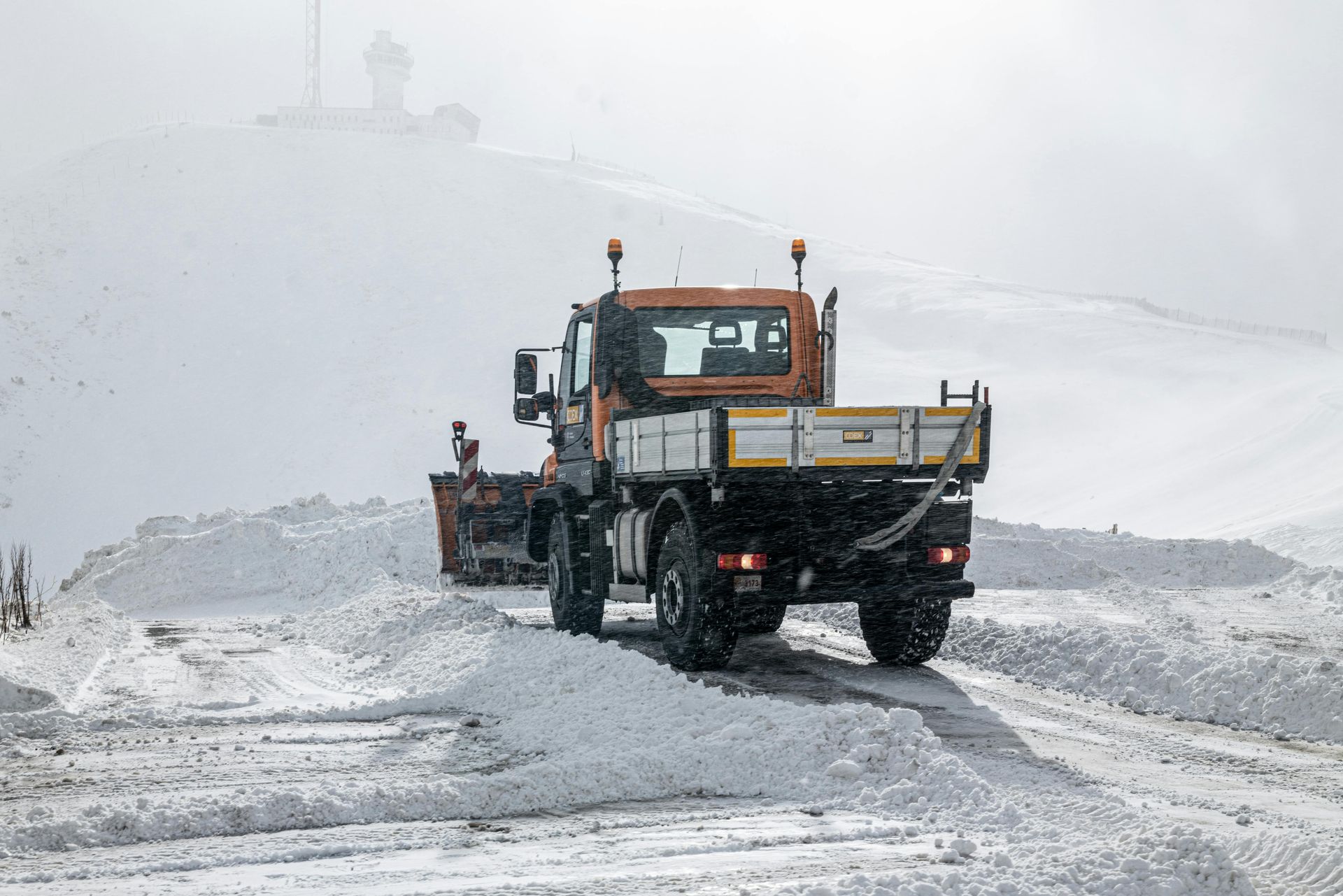 A snow plow is driving down a snow covered road. | Superior Transmissions & Auto