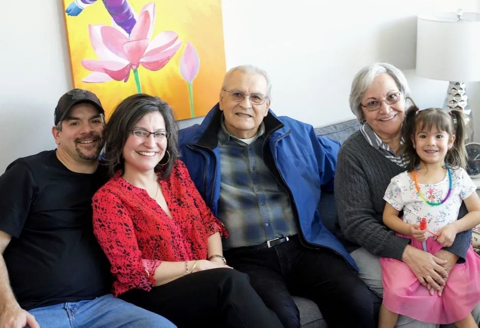 A family is posing for a picture while sitting on a couch.