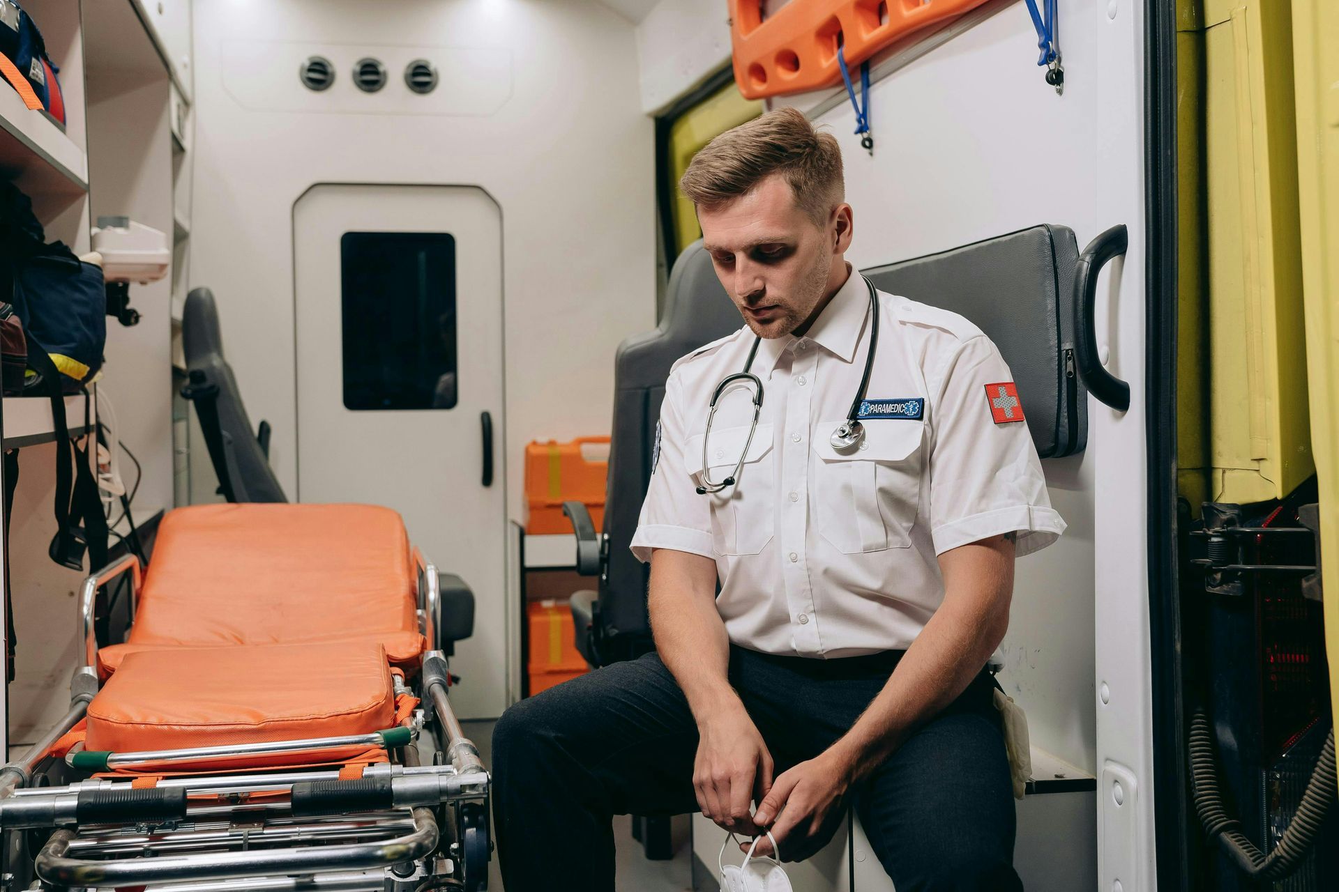 A paramedic is sitting in the back of an ambulance.