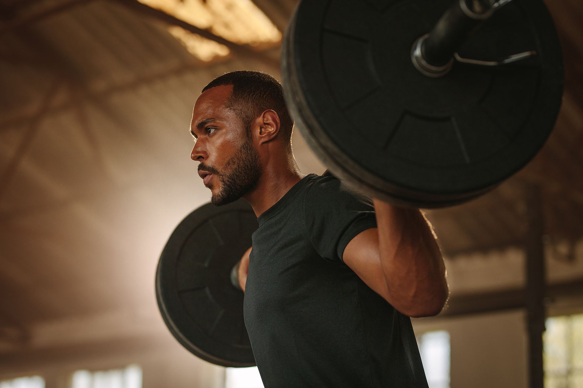 A man is squatting with a barbell on his shoulders in a gym.