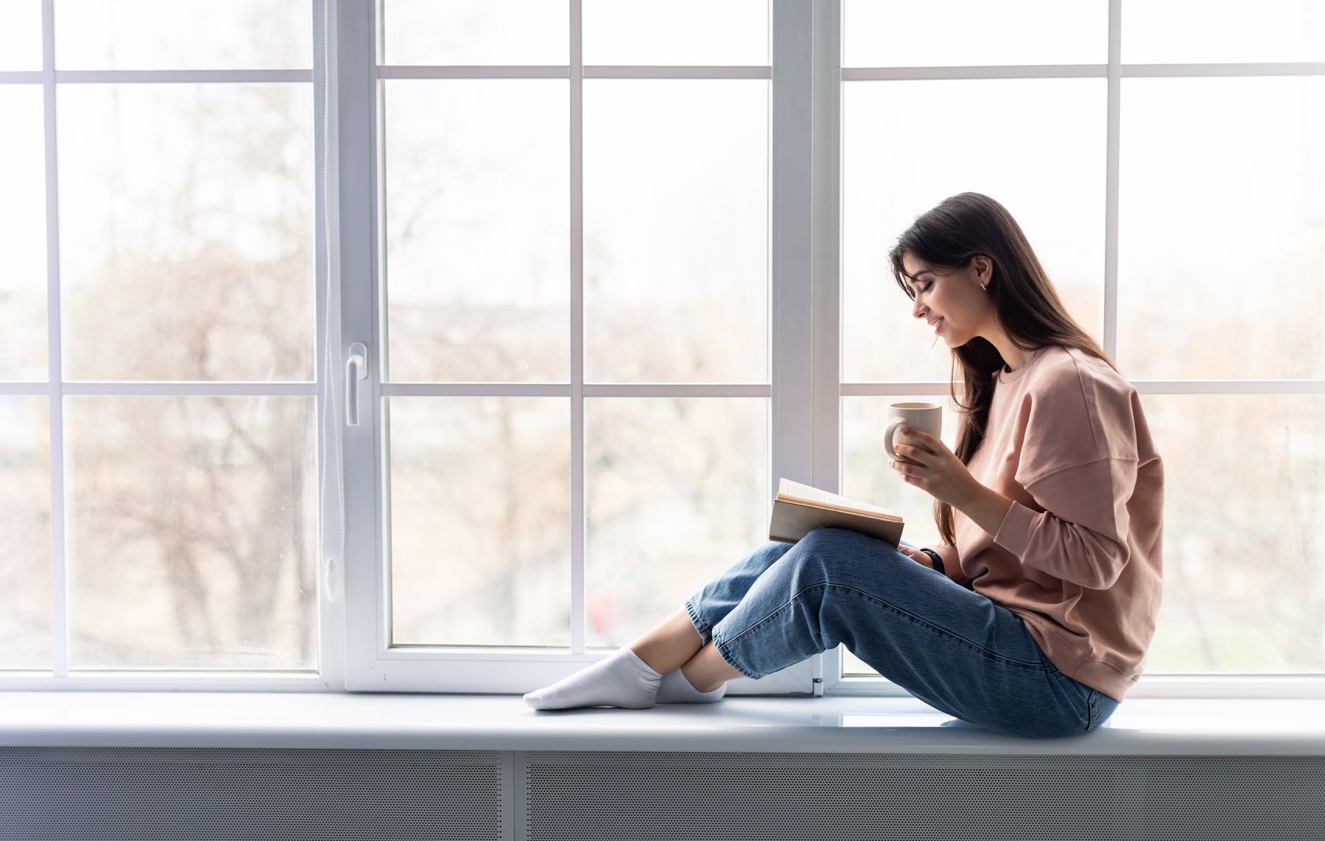 A woman is standing on top of a mountain with her arms crossed.