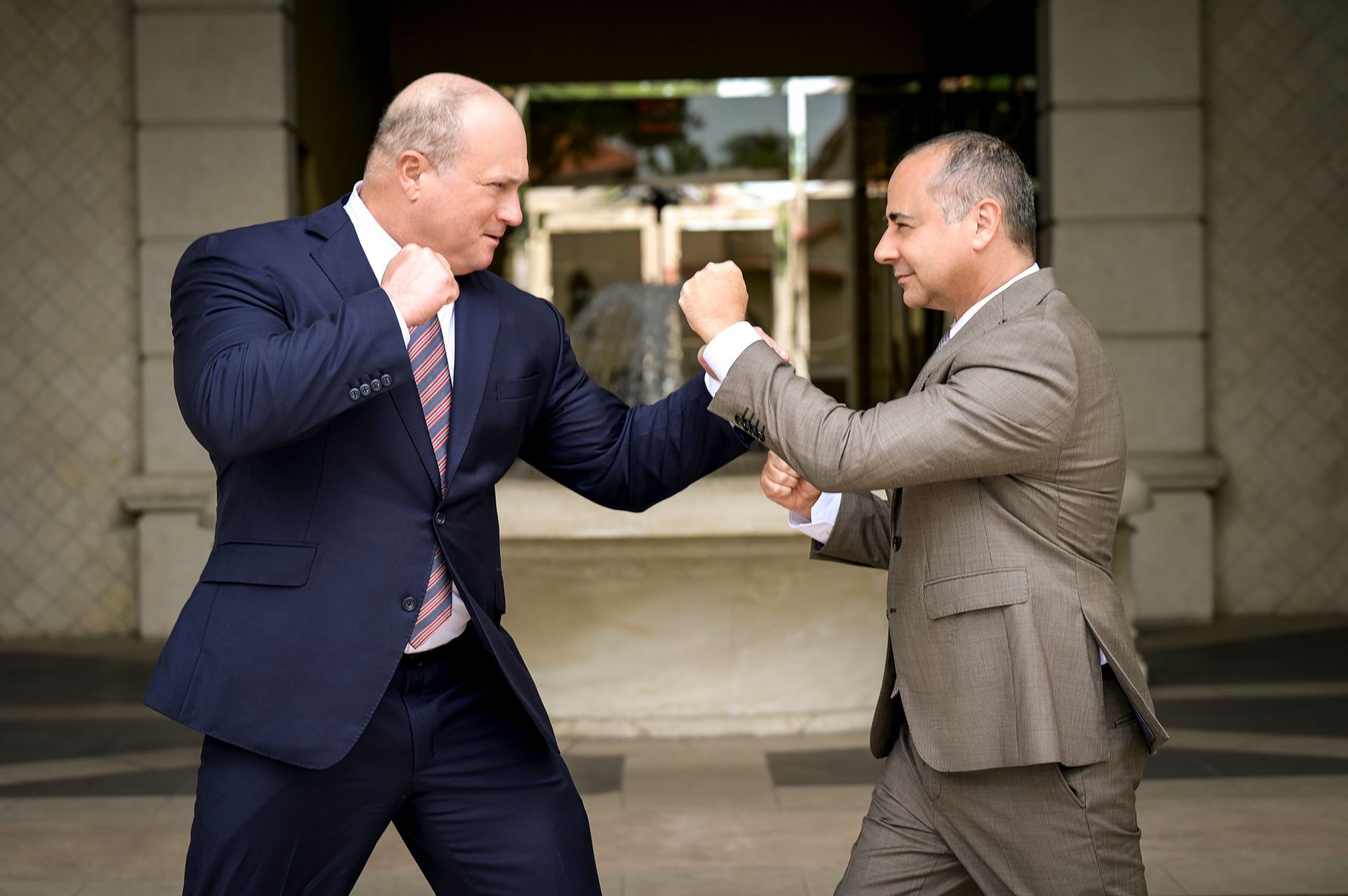 Two men in suits are standing next to each other and shaking hands.