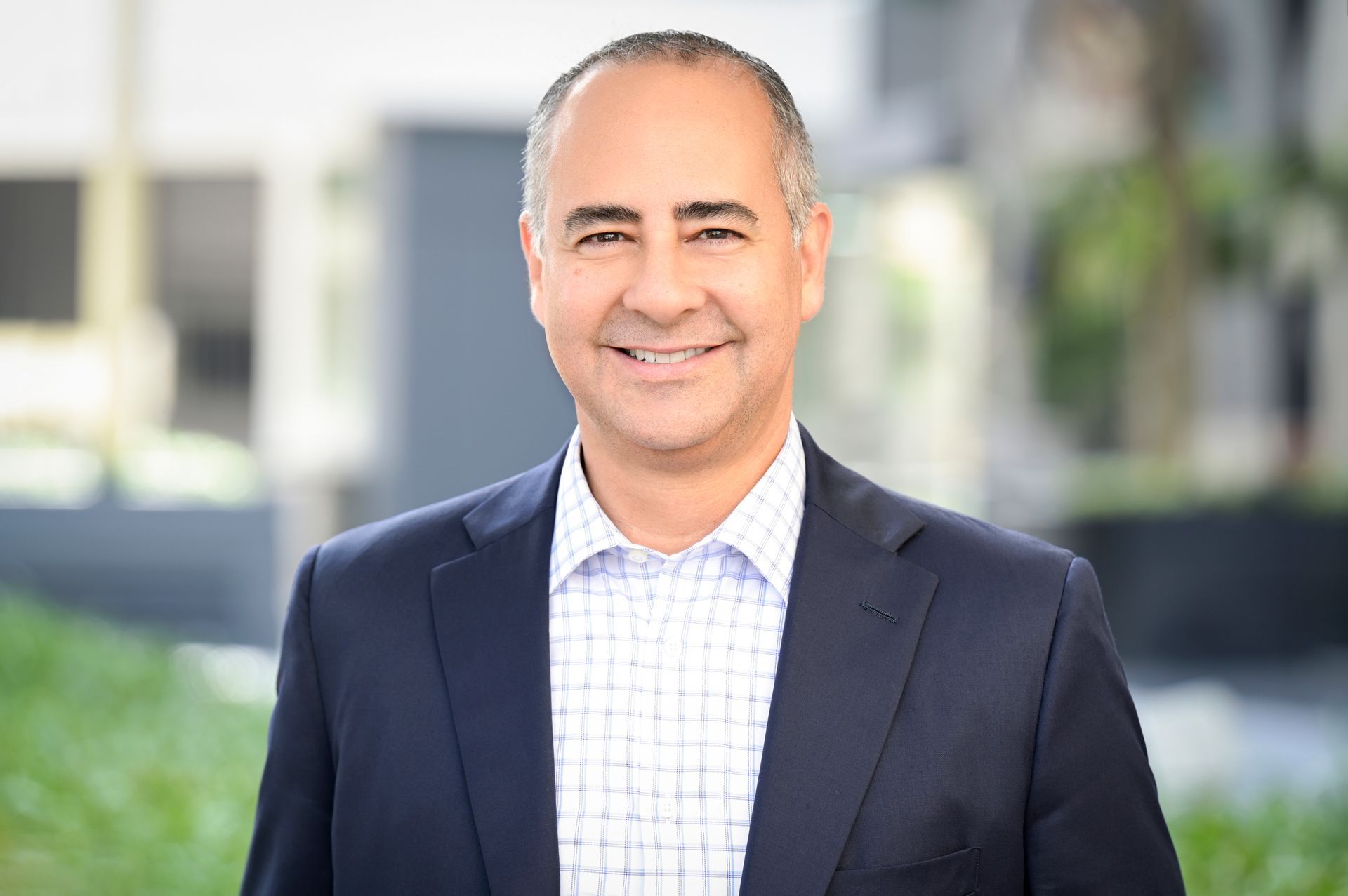 A man in a suit and plaid shirt is smiling for the camera.