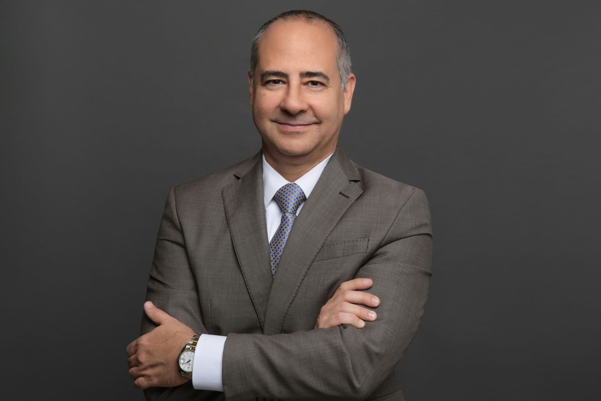 A man in a suit and tie is standing with his arms crossed.