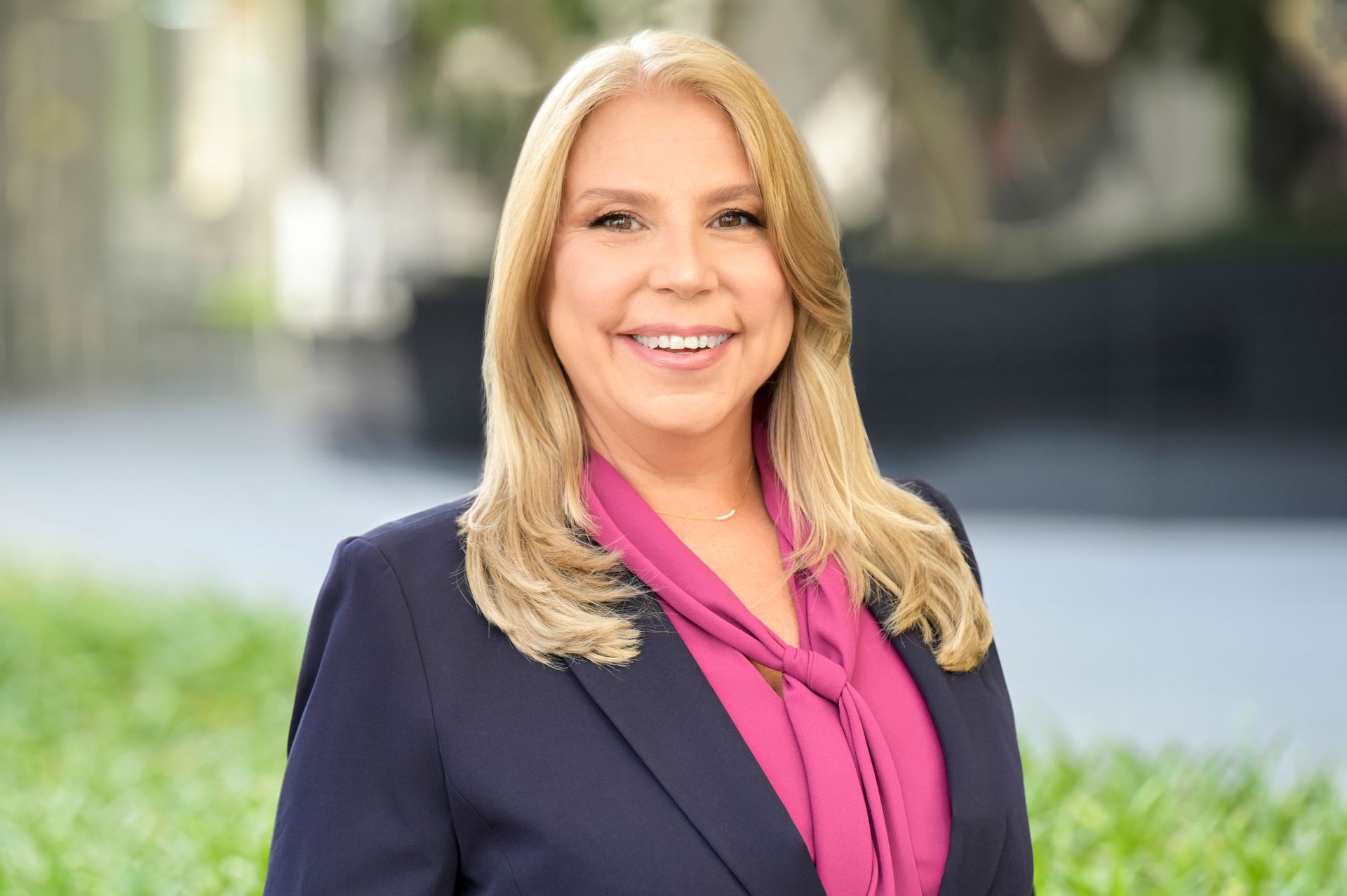 A woman in a suit and pink shirt is smiling for the camera.