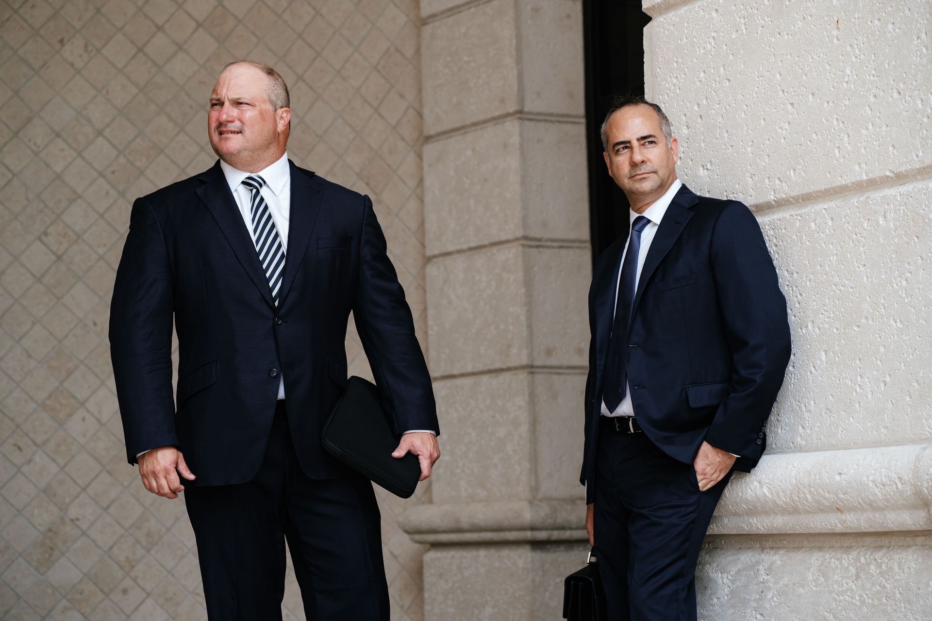 Two men in suits and ties are standing next to each other.