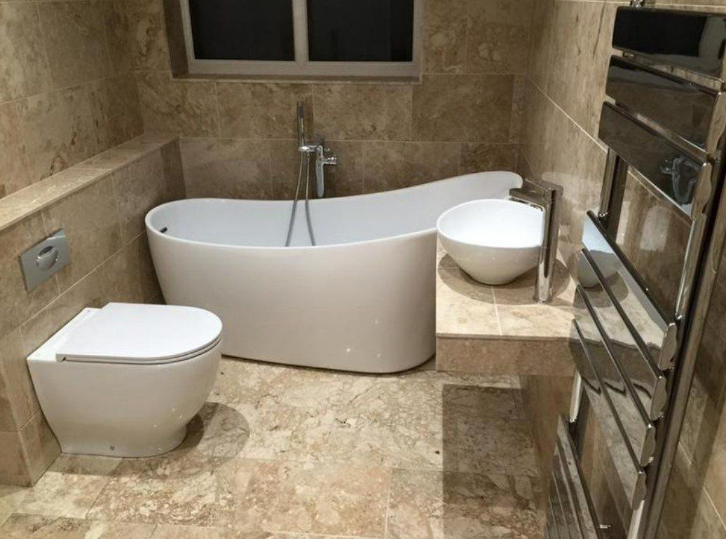 Picture of a new luxury bathroom suite fitted by plumbers Sheffield with white bath and brown marble effect tiles