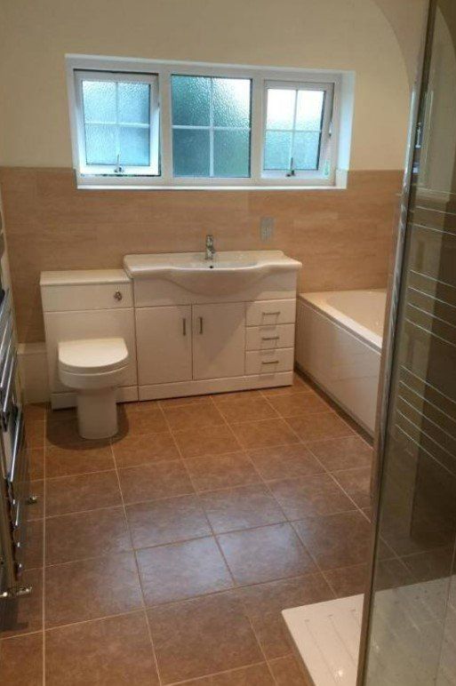 Picture of a new bathroom fitted by Plumbers Sheffield with light brown tiles and white sanitary ware