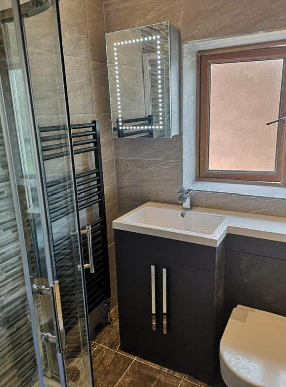 Picture of a new bathroom with walk in shower, towel rail, and vanity unit installed by Plumbers Sheffield