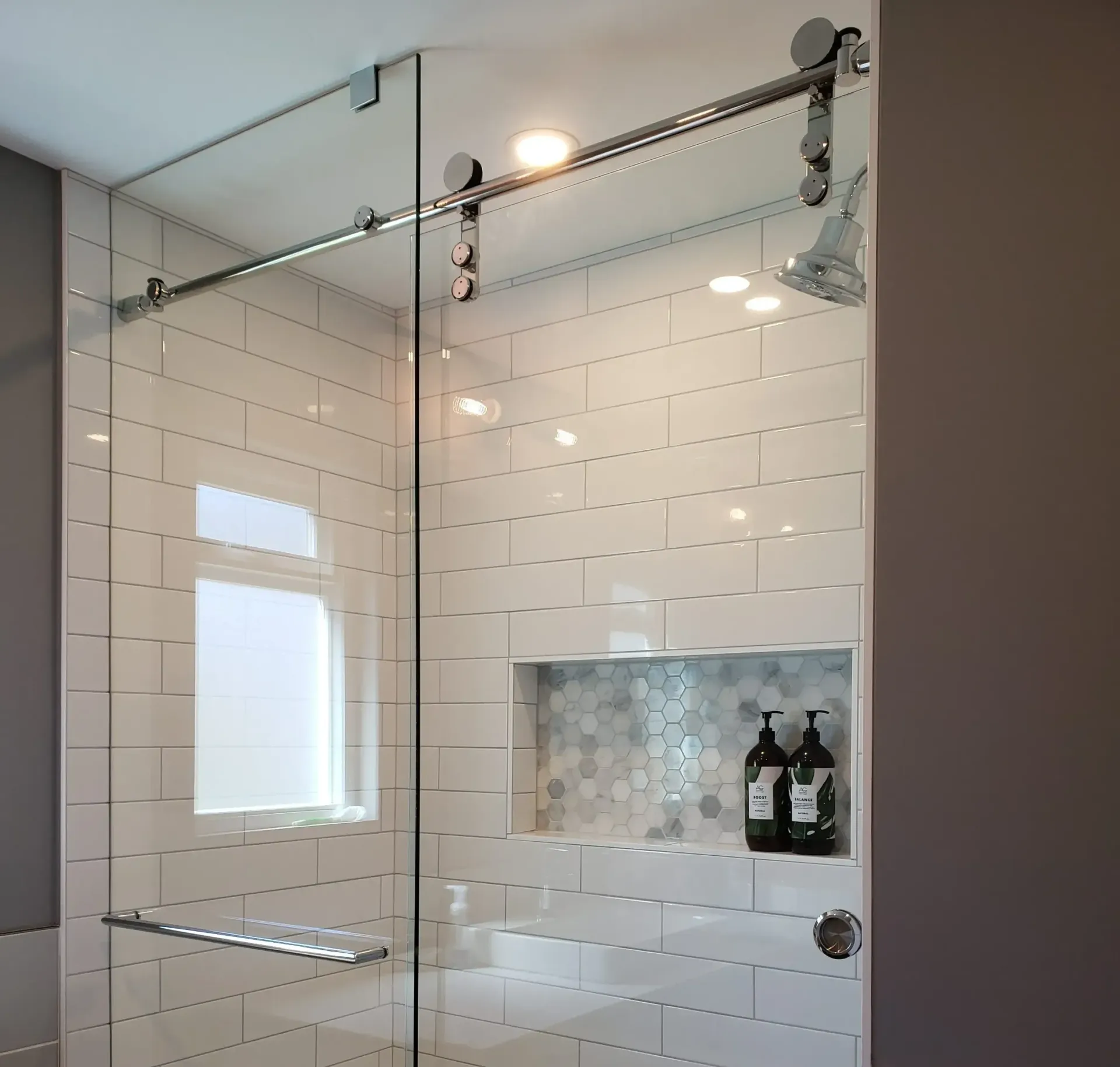 A bathroom with white tiles and a sliding glass shower door