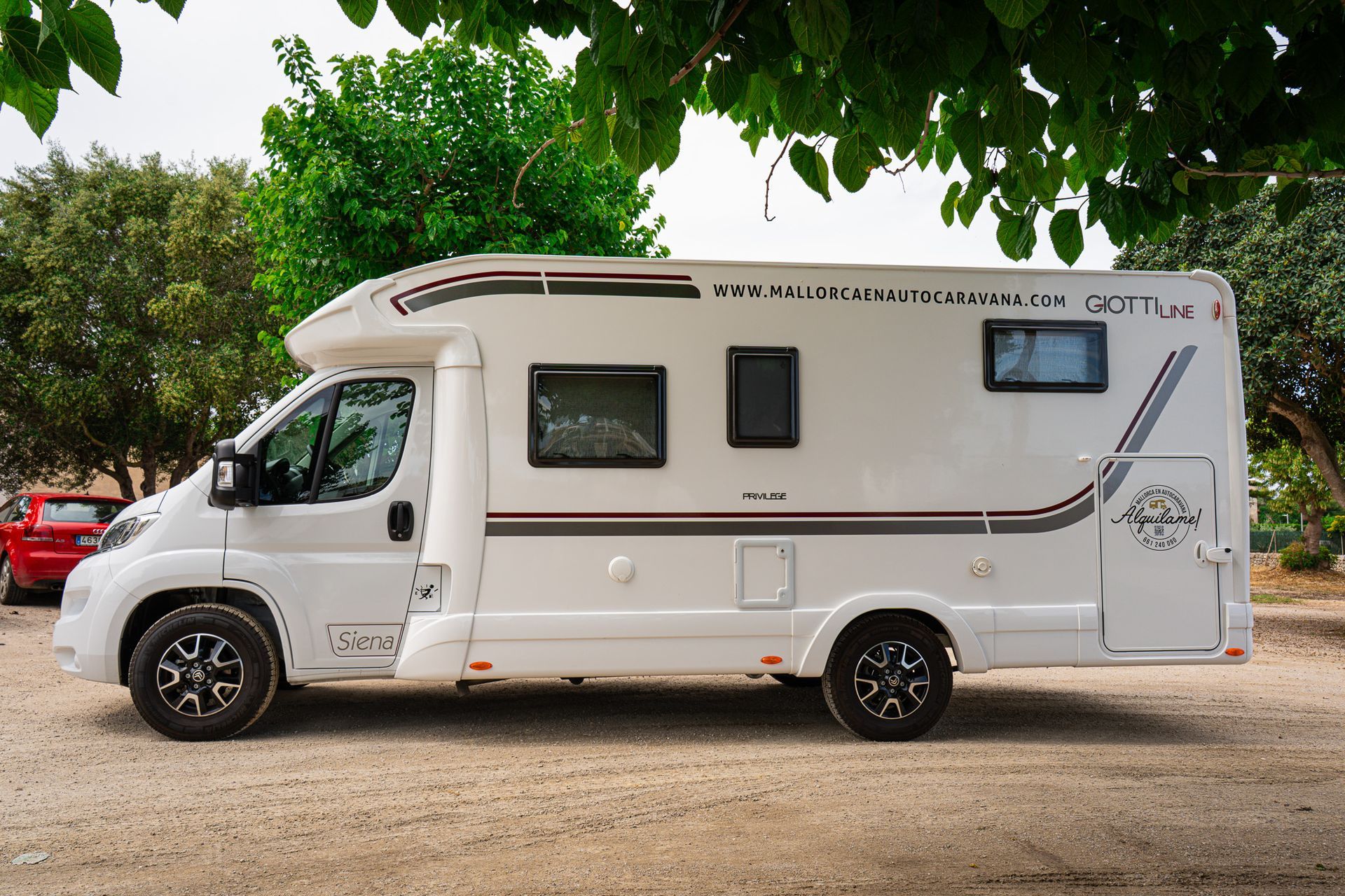 Una autocaravana blanca está estacionada en un terreno de grava.