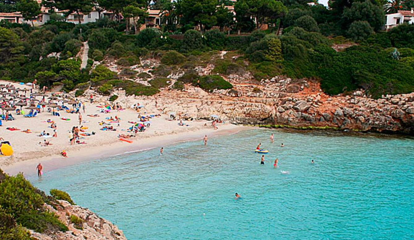 Una playa con mucha gente y gente nadando en el agua.