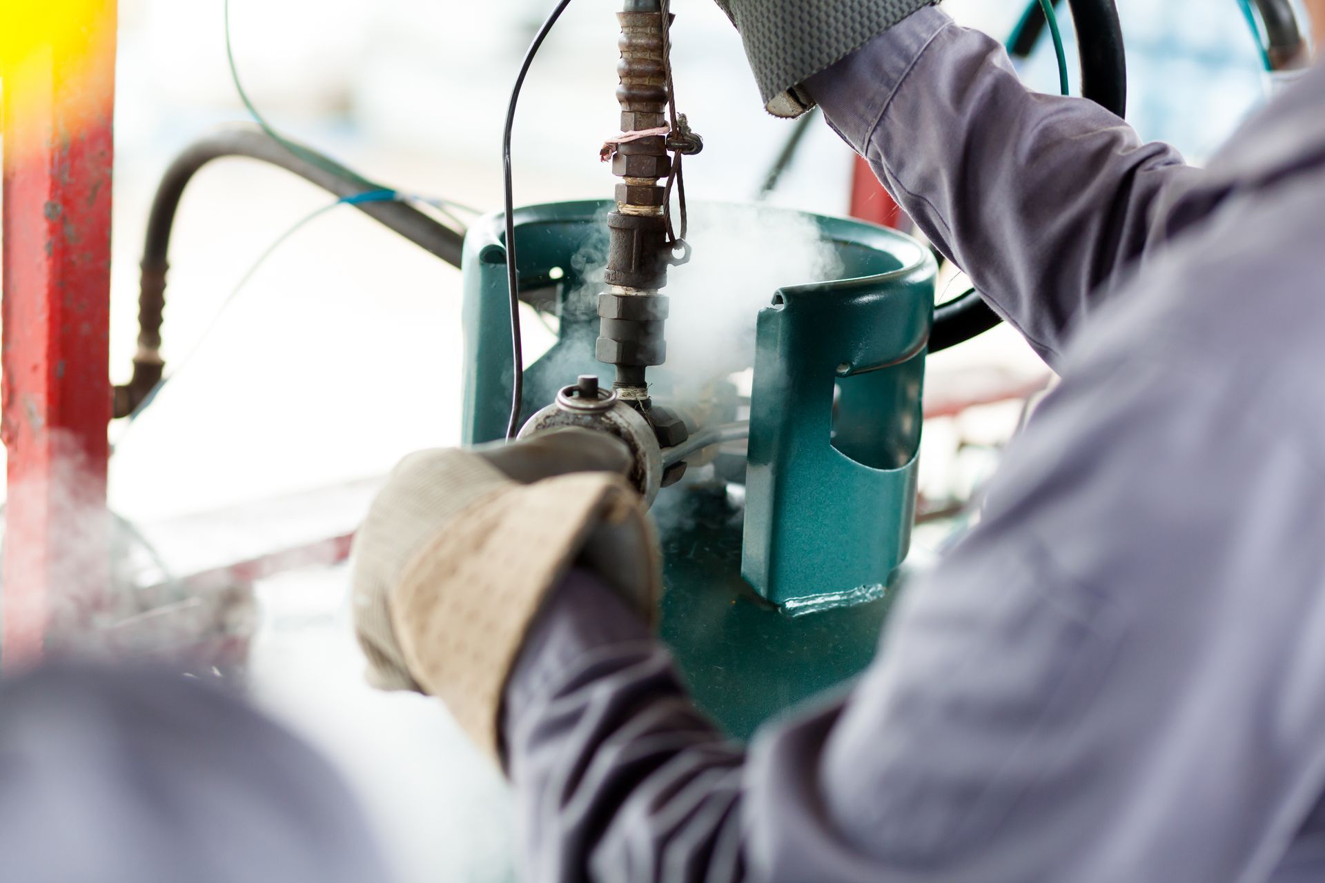 Worker adjusting valve on gas cylinder with visible frost and vapor. Worker adjusting valve on gas cylinder with visible frost and vapor.