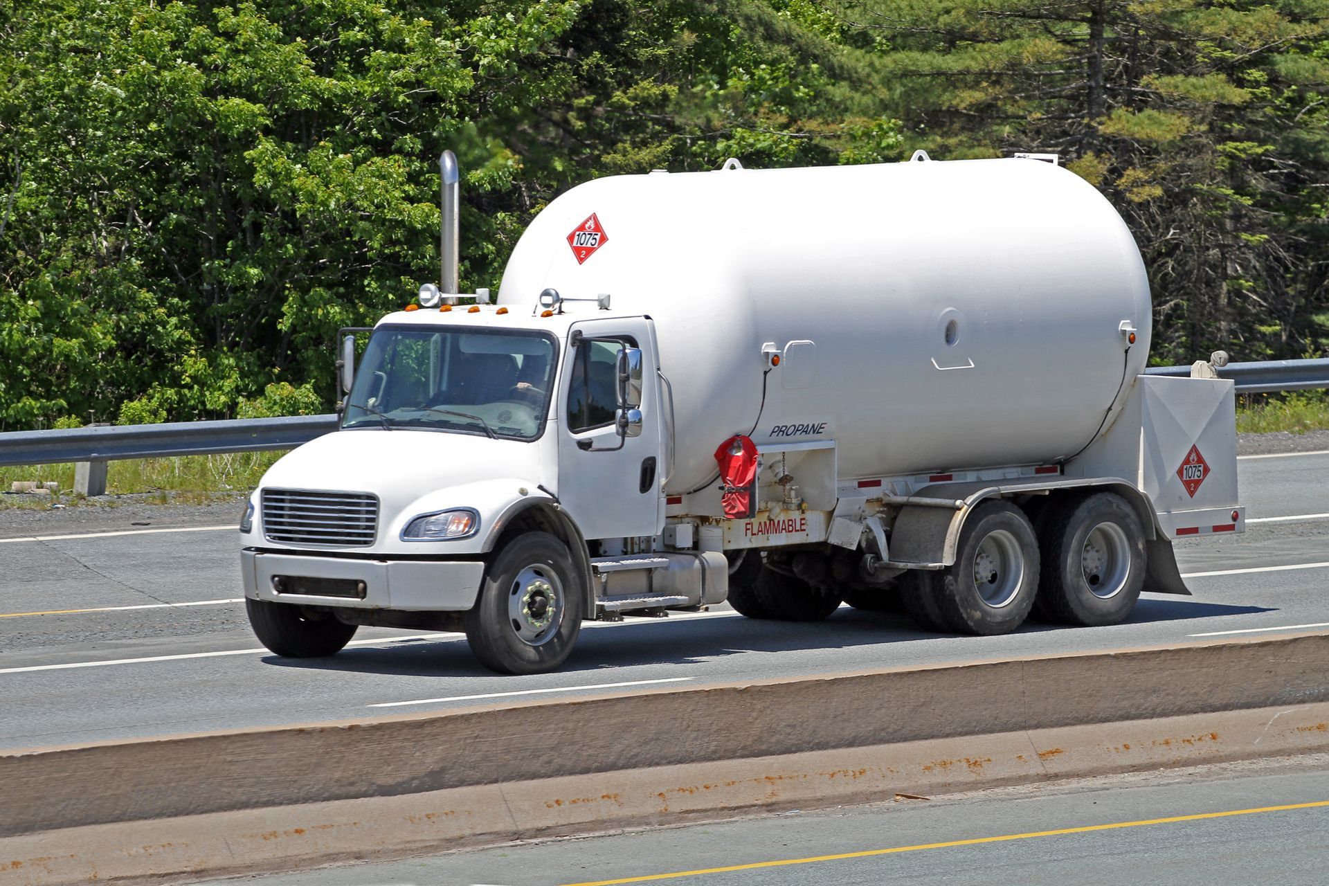 White FLAMMABLE-labeled tanker truck driving on highway.