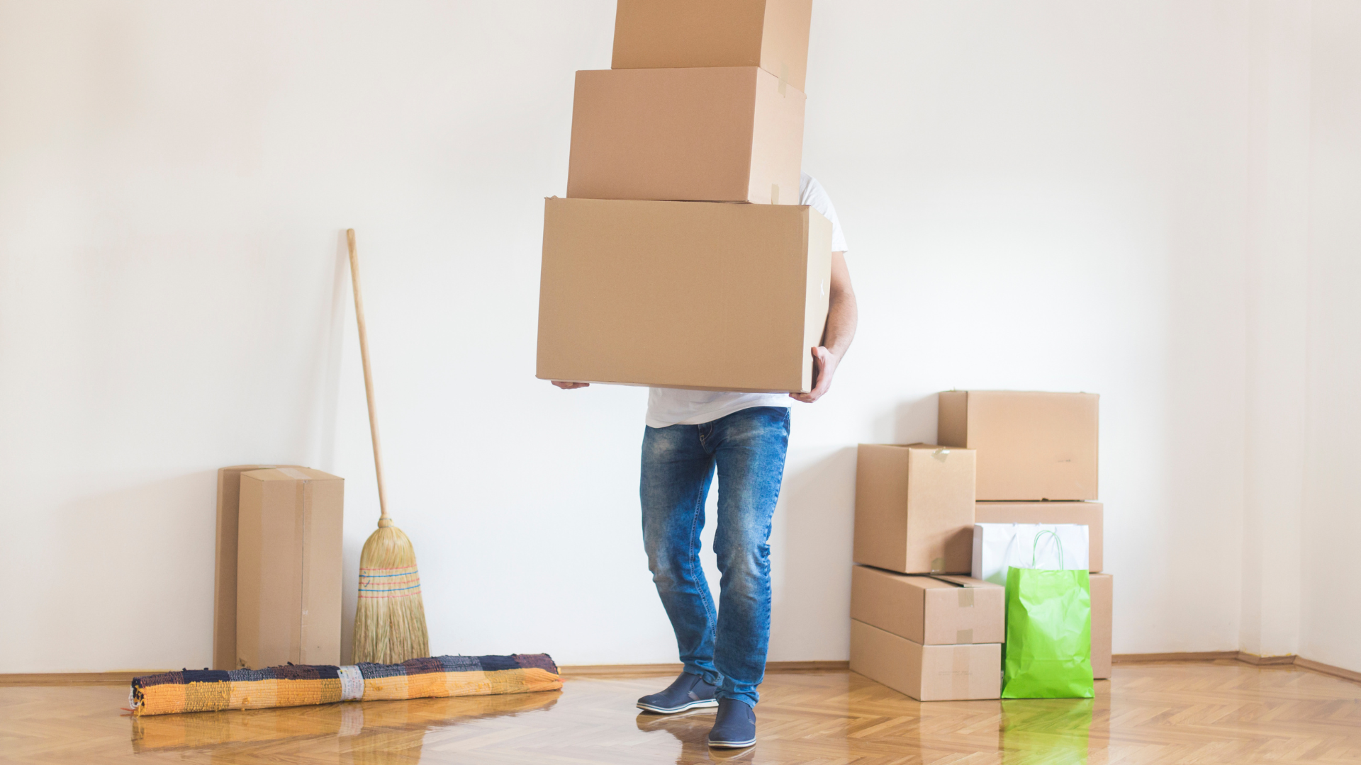 A man is carrying a stack of cardboard boxes on his head.