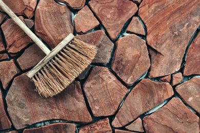 A broom is sitting on top of a rocky surface.