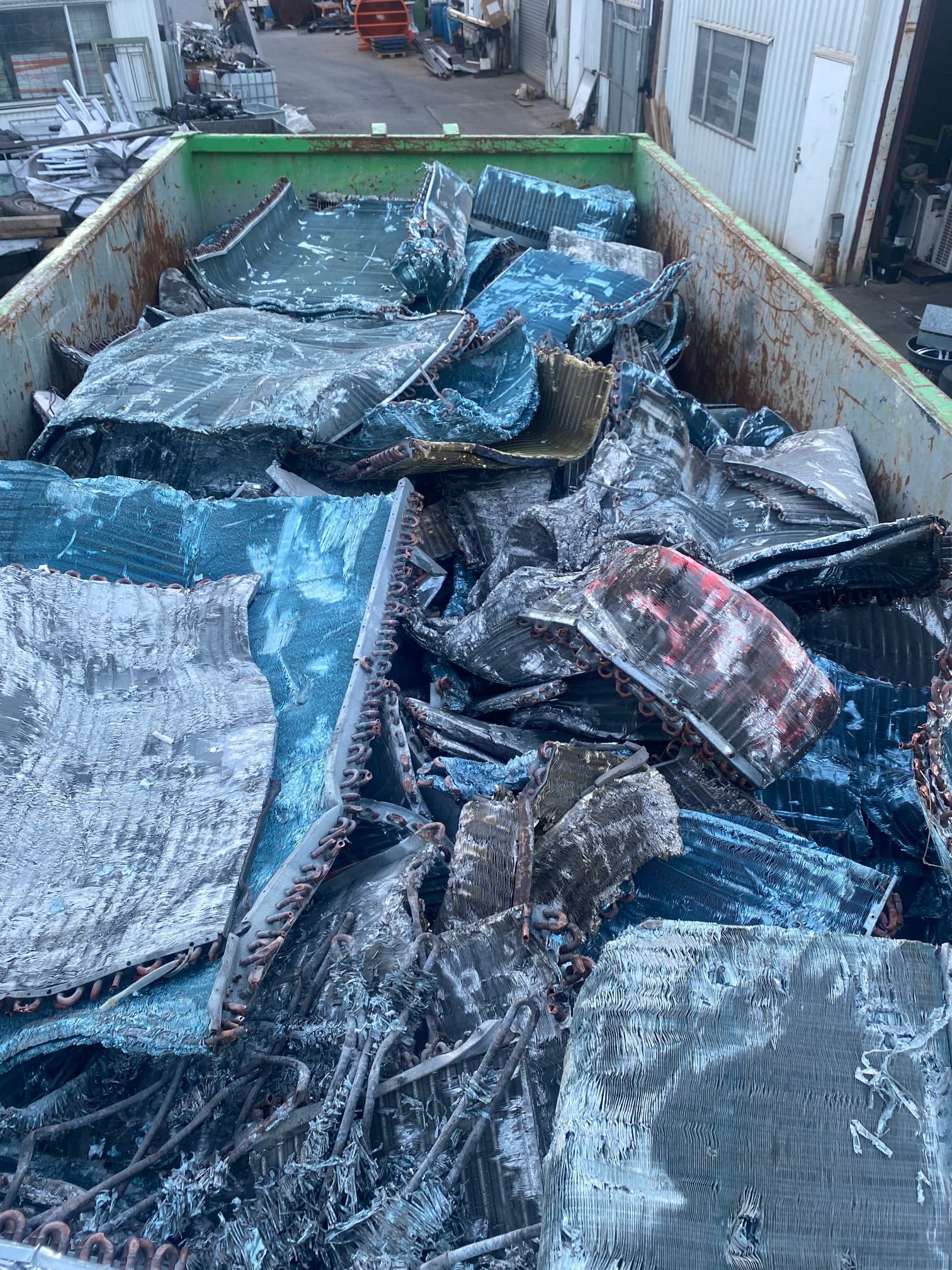 Scrap Metal In A Green And Rusty Container. Blue And Black Components. Outdoors — H&H Metal Recycling in Kenilworth, QLD
