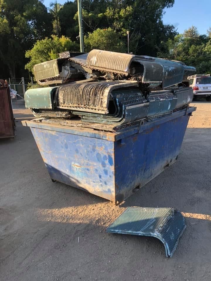 Blue Dumpster Overflowing With Green Metal Parts On A Paved Lot — H&H Metal Recycling in Kenilworth, QLD