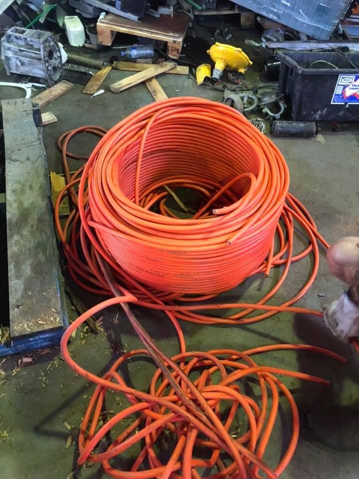 Coiled Orange Electrical Wire In A Cluttered Workshop Setting — H&H Metal Recycling in Maleny, QLD