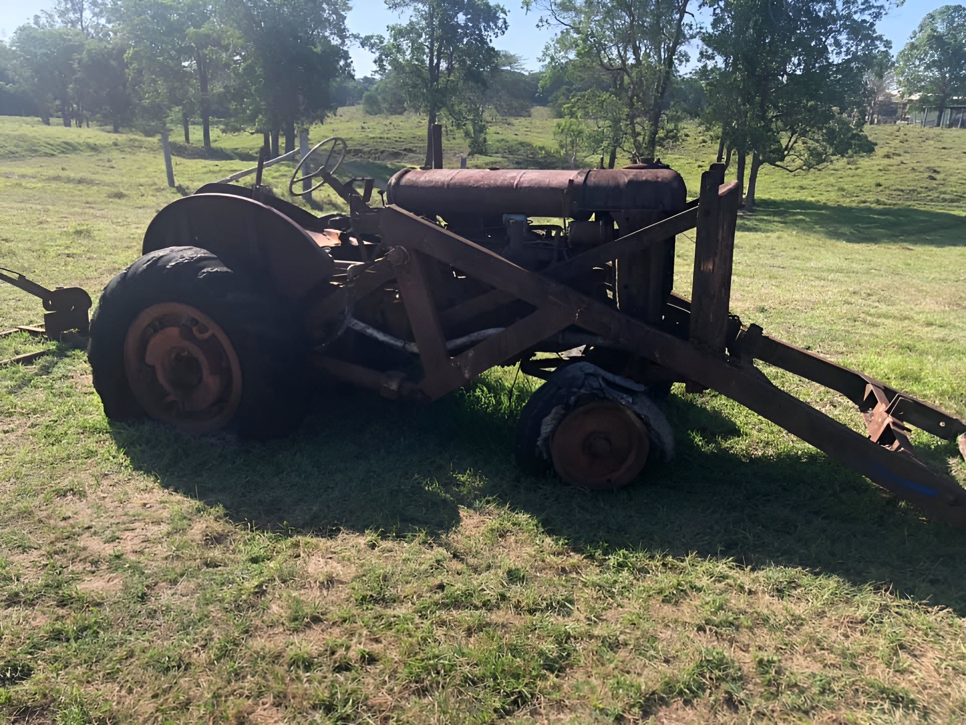 Old Rusty Tractor With Loader In A Grassy Field — H&H Metal Recycling in Maleny, QLD