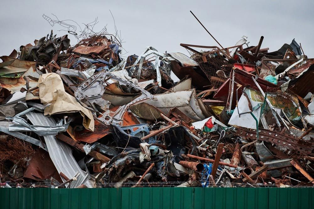 A Pile of Scrap Metal Is Sitting in Front of A Green Fence — H & H Metal Recycling In Kunda Park, QLD