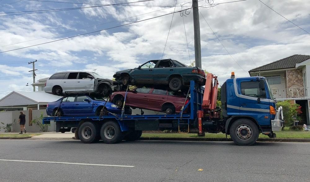 A blue Tow Truck Is Carrying a Bunch of Cars on The Back of It — H & H Metal Recycling In Kunda Park