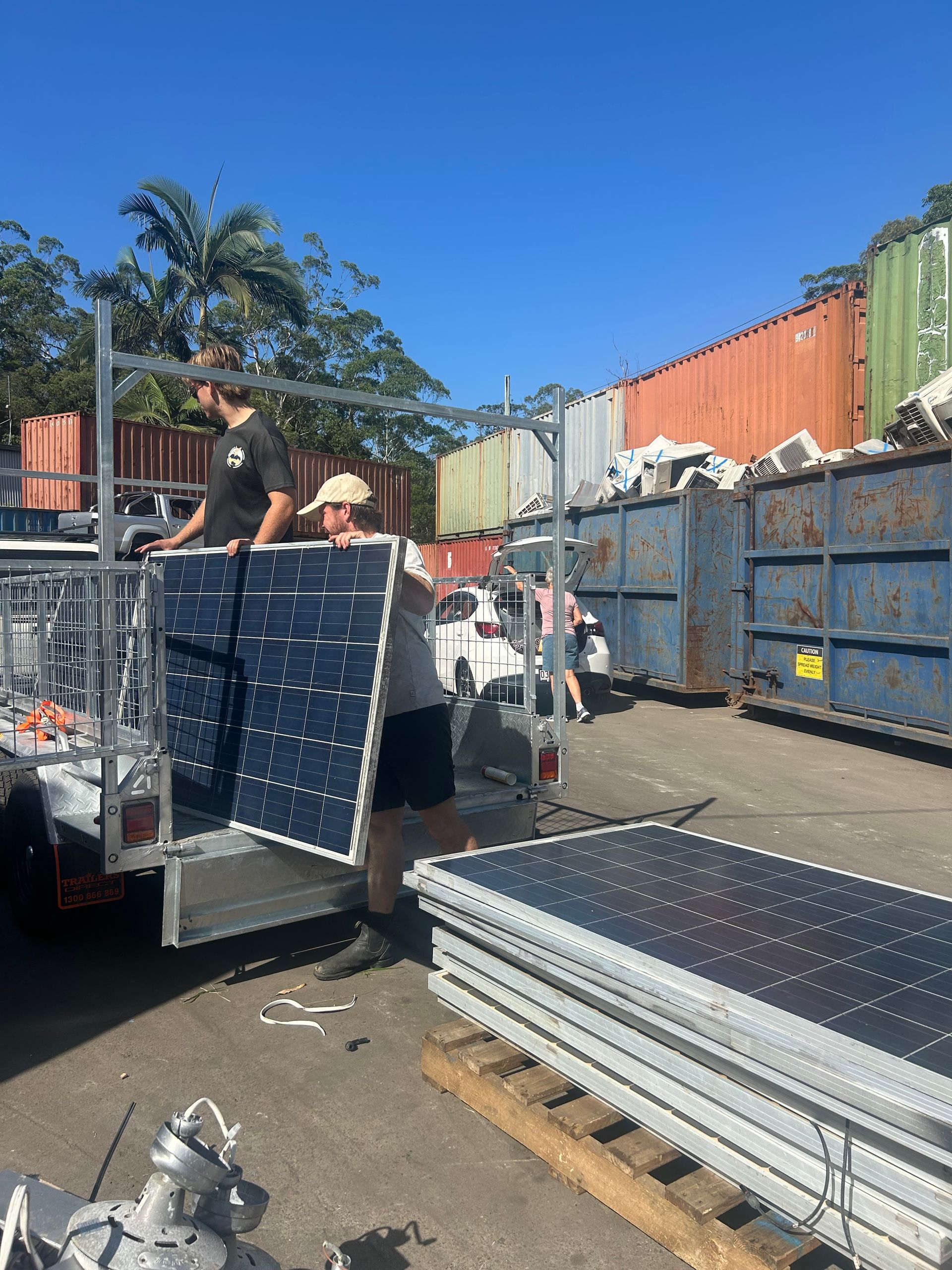 Two Individuals Unload Solar Panels From a Trailer — H&H Metal Recycling in Bells Creek, QLD