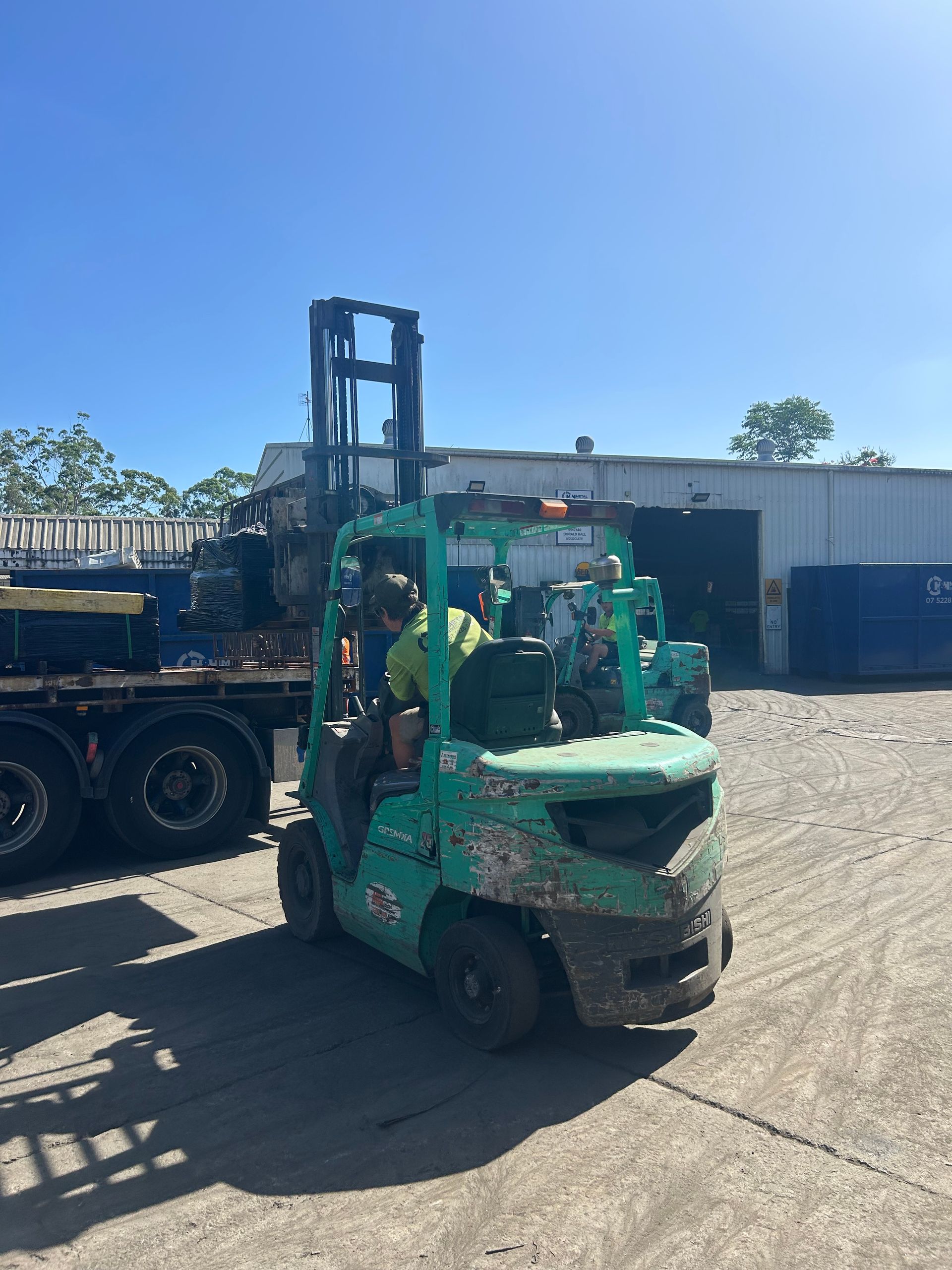 A Green Forklift Operator Works in an Outdoor Industrial Yard — H&H Metal Recycling in Bells Creek, QLD