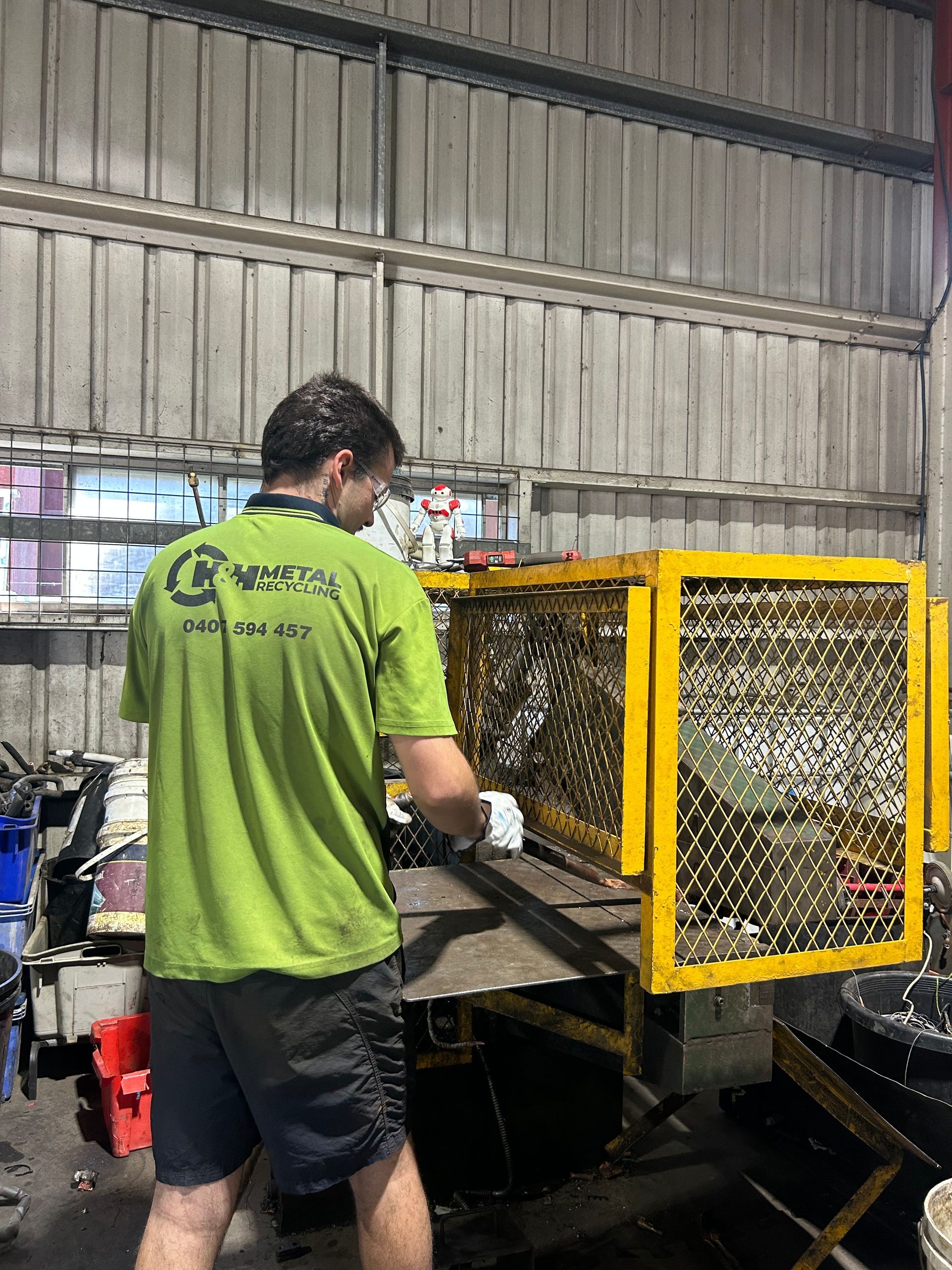 A Person in a Bright Green Shirt Uses Metal-cutting Equipment — H&H Metal Recycling in Beerwah, QLD